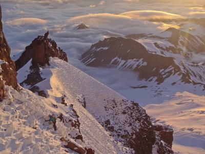 Joe traversing sun cupped snow slopes to pass the prominent gendarme on Curtis Ridge.