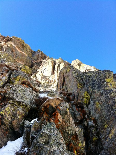 The loose crux of P1 (foreground) with the crux pitch in the background. Pitch 2 ascends the dark dihedral in the middle of the brightly lit wall above.