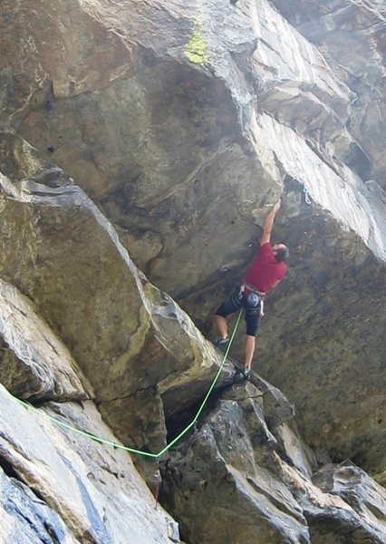 Midway through the crux, making a big reach out to the lip of the largest roof.