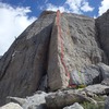 Starting about 10' right of the sun/shade arête, move up and left toward the arête, then continue up to the blade.  Climb and traverse the blade to the anchors.