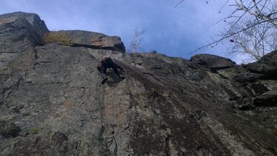 Climber clearing the second ledge and heading right onto small slab.