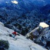 Myles Moser following the P6 headwall cracks on Stormy Petrel, with the Pedestal illuminated in the fading afternoon light.