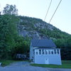 The approach trail (left of the boulder) and the cliff in the background.