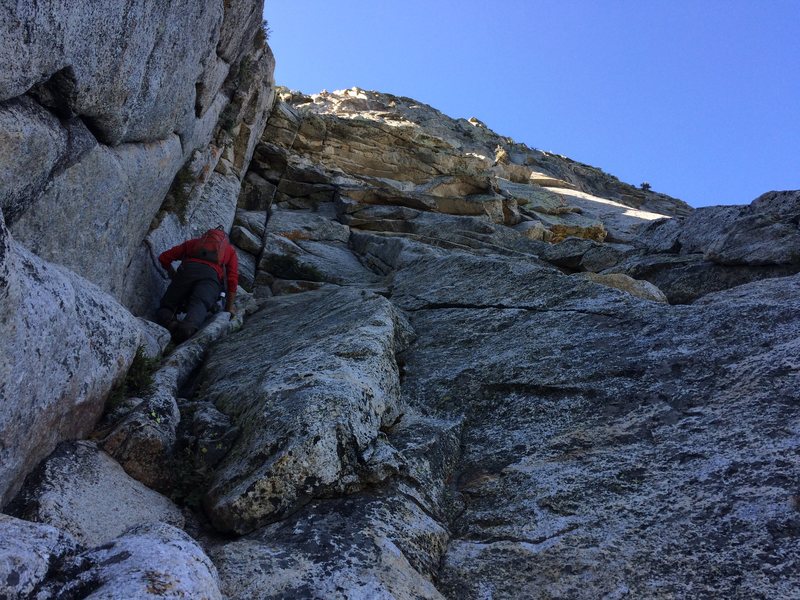 Free soloing 4th class P1 to a belay ledge, 20-30' below the roof, 15' right of the dihedral 