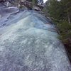 This is the view up from the top of P4 (at the gear anchor above the finger cracks). Head directly up, across the moss streak. It's easy climbing, but completely runout, no pro for about 100 feet until you get to the rock bulge with a brown shrub just right of the center of this photo. You'll find pro near the shrub. Trending right from there gets you to a thread belay at a jumble of rocks. It had rained 2 days before, so this area was pretty wet.