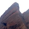 Cross from the top of the tower over the face of the arête. Route continues up through the crack in the roof. 