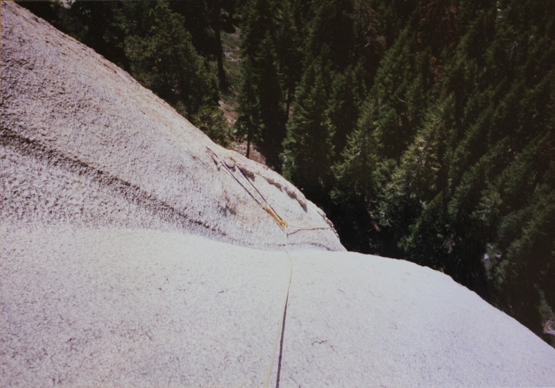 Long slings draped over horns before climbing down into the easiest way up the face of the dome the water chute. Photo shows short steepest section of the chute before easier climbing above. First ascent photo.