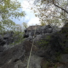 Climber approaching the top of route, served by the right hand side set of anchors, a bolted route.
<br>
   A blue rope can be seen on left which is in the other central top anchor.