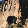 Photo of Psycho Killers sector with the 3 prominent cracks visible  in order from left to right: Psycho Killer, Barracuda, and Burning Down the House, with a climber half way up the route.