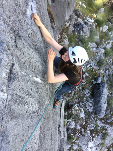 Blurry cell phone shot of Amanda sticking the crux reach.