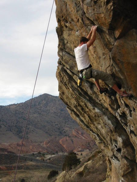 Matching hands for the Nautilus crux.<br>
 <br>
Tall? Dyno with the right to the hidden, incut, blackrock, pocket (out of the photo).  Less Ape-ish?  Then use the 5.11 pinch-side-pull intermediate hold, a scrap of chalk in the photo.<br>
<br>
The second bolt is just under the climbers's right elbow.  The first bolt is hidden in the shadows, located four tenths of the distance from his foot to the bottom of the photo.