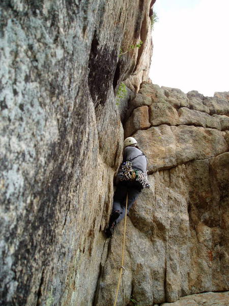 Photo by Luke Clarke.<br>
<br>
In the middle of the crux. Awkward hand jamming followed by a long reach to a wide jam and then stem out left.<br>
<br>
The exit crack is visible in the orange rock directly above the rightmost of the two bushes.