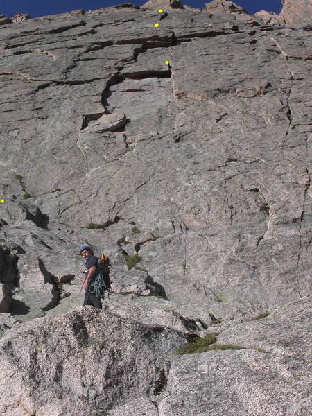 Mike Amato below the start of the route. The prominent inset on the first pitch is directly above Mike.  The start of the climb and the first three belays are shown by yellow dots.