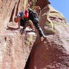 Mark completing the crux on the third pitch.  Palm down with the left hand and step the left foot onto the lip of the overhang.