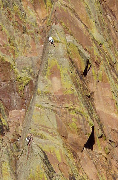 The previous photo cropped to show a close up. The belayer at the bottom is down and right from the 5.8 hand travese pitch of Yellow Spur. The Mellow Yellow crux roof is to the belayer's right. Psycho Pigeon climbs up from the belayer, diagonals right to the arete, around the arete and up the slab. The leader is just below the Yellow Spur belay below the pin ladder.