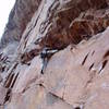 Placing a piece to protect the ceiling. Although there are several good footholds on the wall below, it's usually easist to keep the right leg or foot on the ledge.