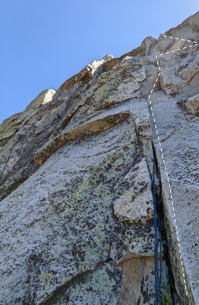 Just shy of the P4 belay ledge described in the book. There are two sets of "closely spaced pins" on this pitch; go to the higher ones that are a few feet below the "superfluous bolt". If rope drag is an issue, a lower anchor can be built.