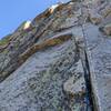 Just shy of the P4 belay ledge described in the book. There are two sets of "closely spaced pins" on this pitch; go to the higher ones that are a few feet below the "superfluous bolt". If rope drag is an issue, a lower anchor can be built.