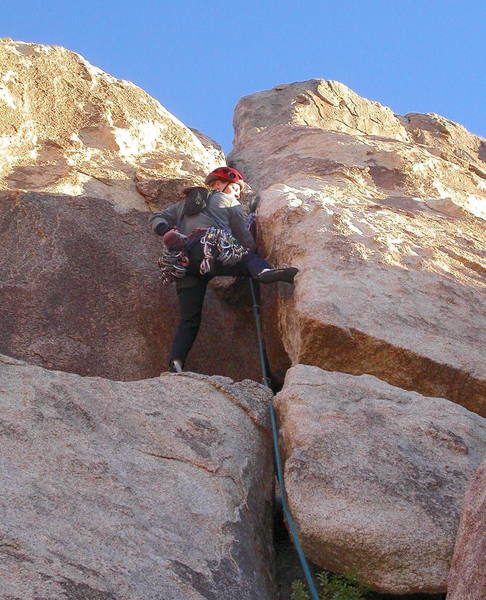 Christa Cline about to step right onto the face by the roof.  Big holds make the move easier than it looks.